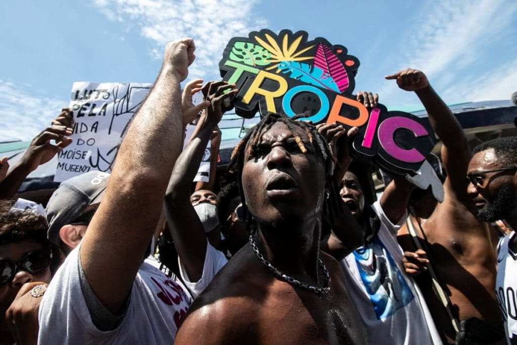 Personas arrancan el cartel de un kiosco en Río De Janeiro. MoÏse trabajaba en un kiosco de la ciudad brasileña. Foto: Bruna Prado, AFP