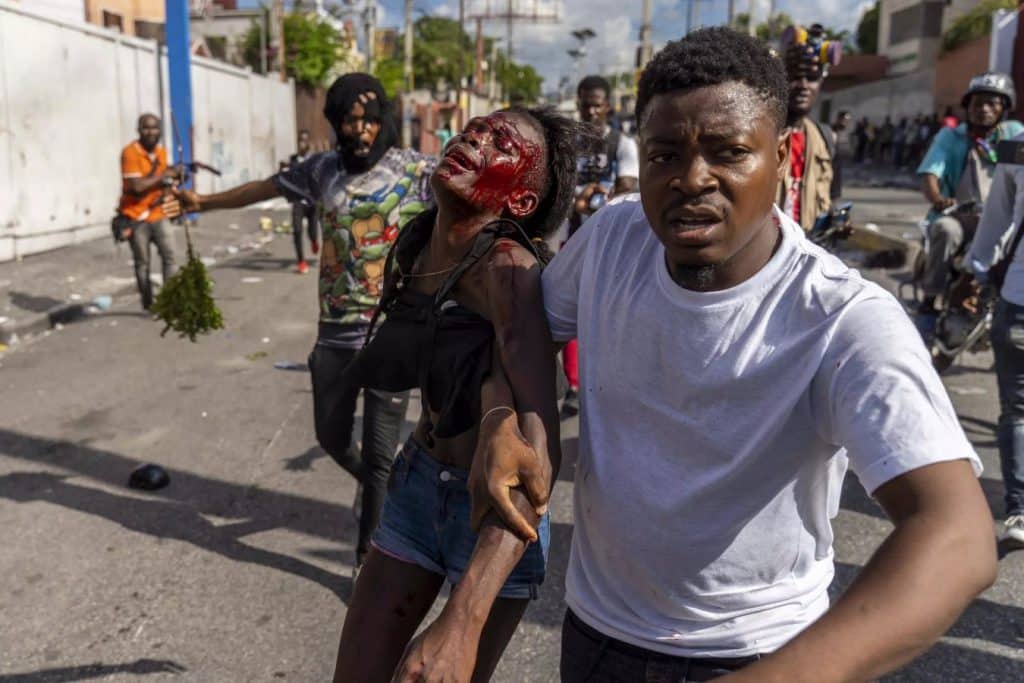 Dos manifestantes corren en las calles de Puerto Príncipe, Haití, l 10 de octubre de 2022. Foto: AFP