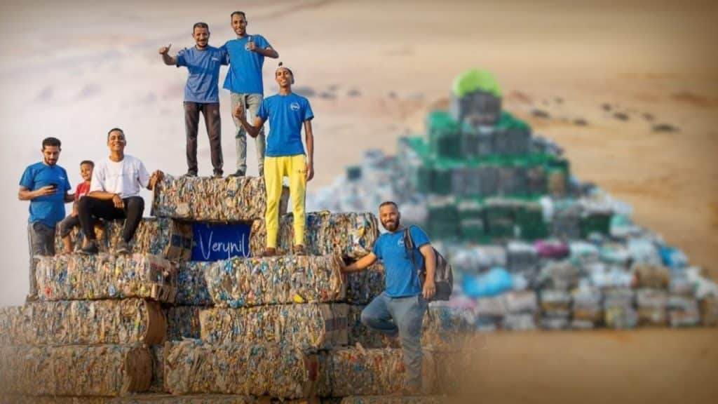 Volunteers of the 100YR CLEANUP movement on top of a garbage pyramid