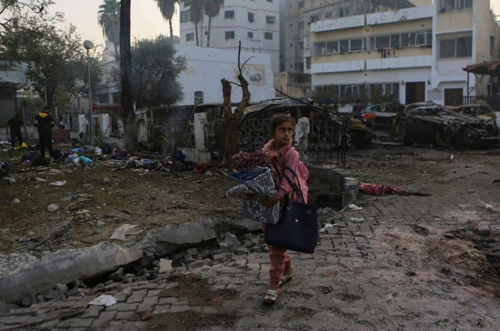 Tras el ataque al hospital de Al Ahli en Gaza, una niña palestina recoge objetos del lugar. (Abed Khaled)