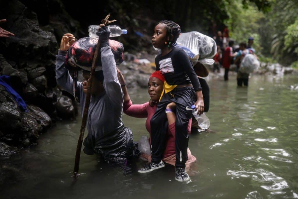 Migrantes haitianos atraviesan cuerpos de agua mientras cruzan el Tapón del Darién desde Colombia hacia Panamá, en su largo y complejo camino hacia EEUU, el 9 de mayo de 2023. (Foto: Ivan Valencia, Associated Press).