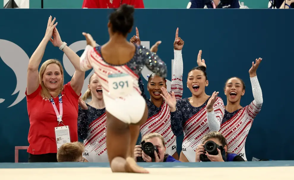 Simone Biles, estrella de la gimnasia, es aclamada por sus compañeras de equipo tras concluir su rutina en el suelo, la cual les garantiza la medalla de oro.