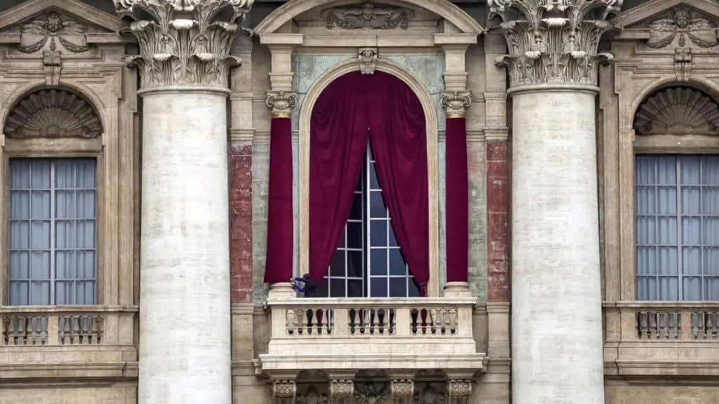Un trabajador coloca el paño rojo en la logia de la Basílica de San Pedro, por donde saldrá el nuevo papa. Gregorio Borgia / AP
