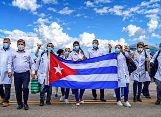 Cuba desafía a EEUU: Ahora está desarrollando un fármaco contra el cáncer Brigadistas cubanos sostienen la bandera de Cuba en una pista de aeropuerto.