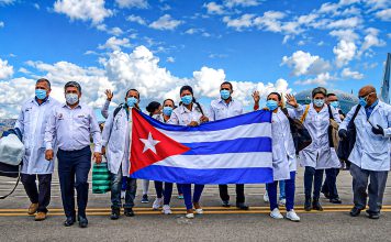 Cuba desafía a EEUU: Ahora está desarrollando un fármaco contra el cáncer Brigadistas cubanos sostienen la bandera de Cuba en una pista de aeropuerto.
