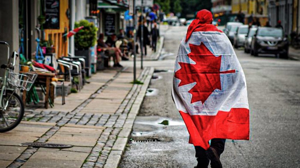 Ciudadano canadiense camina por una calle de Ottawa con una bandera de Canadá.