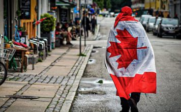 Proponen eliminar nombre de Trump de una avenida en Canadá Ciudadano canadiense camina por una calle de Ottawa con una bandera de Canadá.