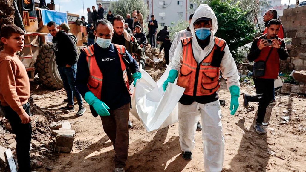 Personal de defensa civil traslada un cuerpo entre los escombros en Gaza.
