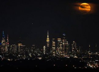 Eclipse lunar parcial iluminará el cielo de Estados Unidos Eclipse lunar de tonalidad rojiza sobre el horizonte iluminado de una ciudad de Estados Unidos.