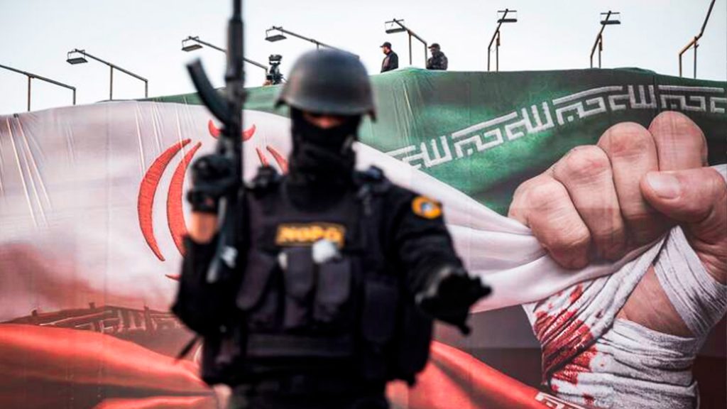 Fuerzas especiales de la policía de Irán vigilan una zona de Teherán frente a una bandera iraní.