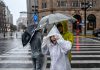 China refuerza respuesta de emergencia ante tifones y tormentas Personas cruzan una calle de China bajo una intensa lluvia con paraguas y ponchos.