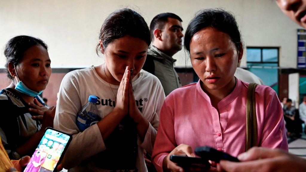 Peregrinas esperan información en el Himalaya tras un desastre mientras revisan sus teléfonos.