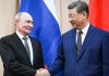 Organización de Shanghái reúne a líderes de Eurasia en Kirguistán Vladímir Putin y Xi Jinping se estrechan la mano frente a las banderas de Rusia y China.