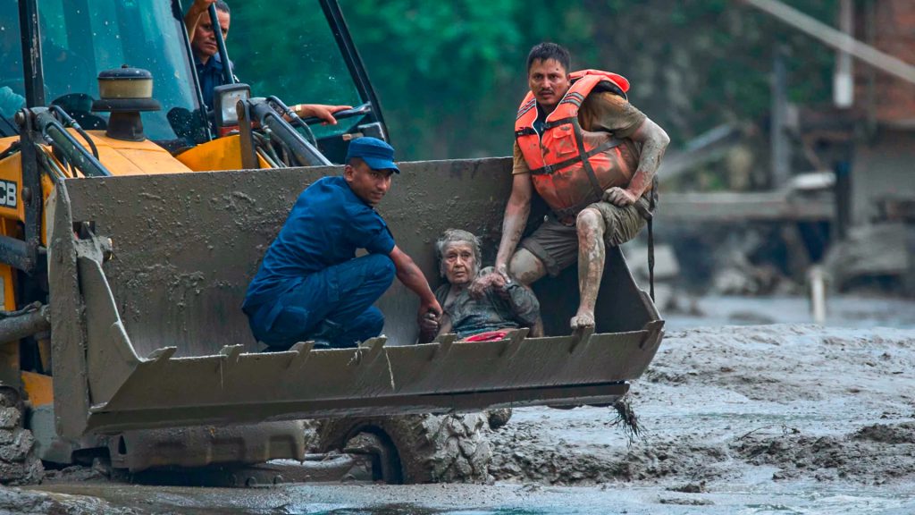 Rescatistas evacúan a una mujer en una maquinaria pesada durante una inundación en Nepal.