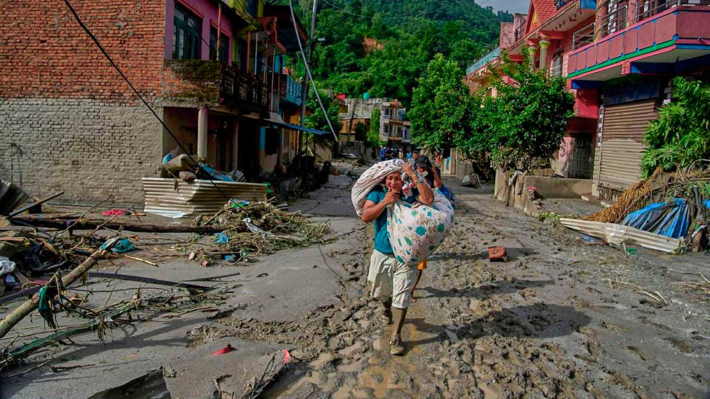 Mujer camina entre lodo y escombros tras inundaciones en Nepal mientras continúan las labores de rescate.
