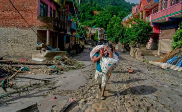 Aumenta la cifra de fallecidos y desaparecidos por devastadora avalancha en Nepal y China Mujer camina entre lodo y escombros tras inundaciones en Nepal mientras continúan las labores de rescate.
