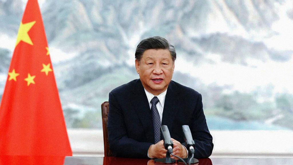 La fotografía muestra a Xi Jinping, presidente de China, sentado frente a dos micrófonos y junto a la bandera china.