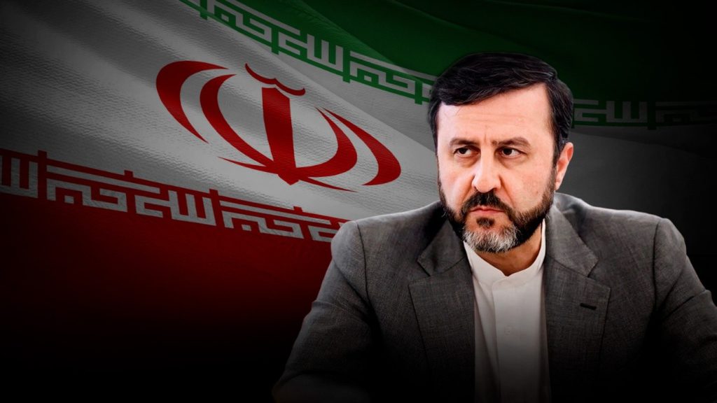 El vicecanciller iraní Kazem Qaribabadi con bandera de Irán al fondo.