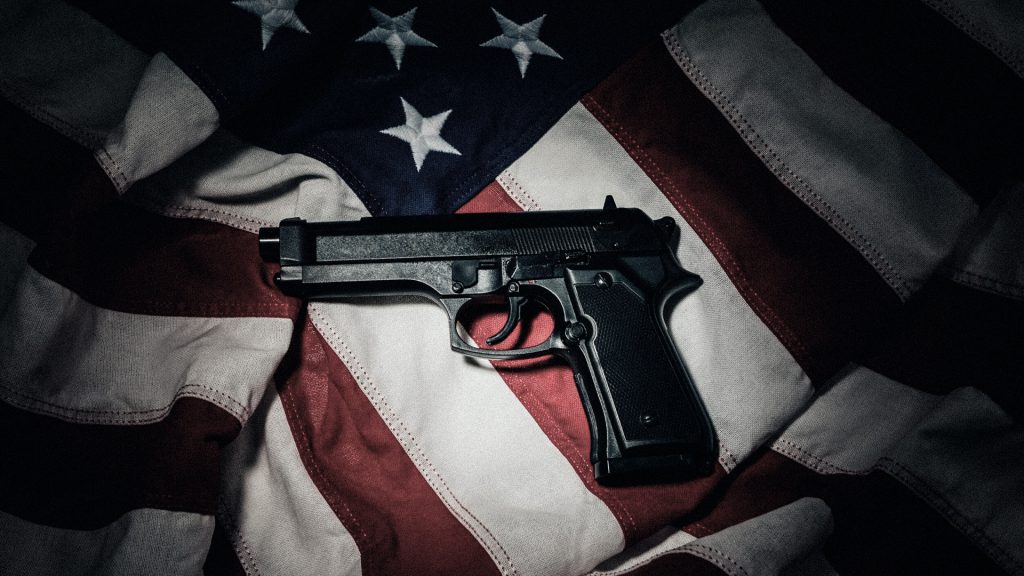 Imagen ilustrativa que muestra Un arma automática sobre la bandera de Estados Unidos, en una imagen alusiva al flujo de armamento hacia México.