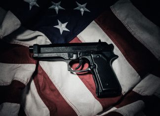 El 71 % de las armas del crimen organizado en México proviene de EE.UU. Imagen ilustrativa que muestra Un arma automática sobre la bandera de Estados Unidos, en una imagen alusiva al flujo de armamento hacia México.