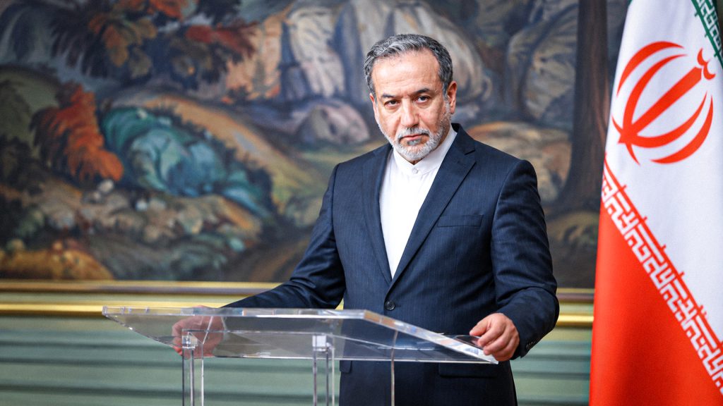 Funcionario iraní durante una comparecencia oficial junto a la bandera de Irán.