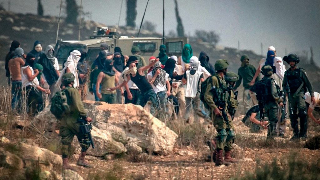 Colonos israelíes y soldados armados junto a palestinos en Cisjordania ocupada.
