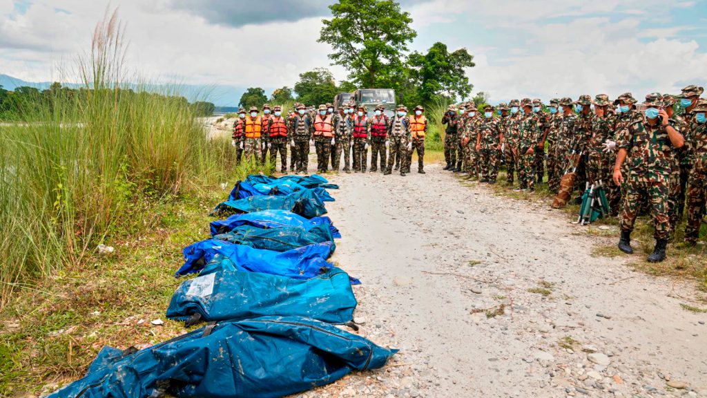 Soldados permanecen junto a cuerpos cubiertos tras una inundación en Chitwan, Nepal.