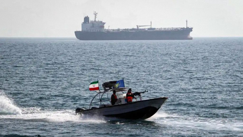 Lancha militar iraní navega por el Golfo Pérsico junto a un buque.