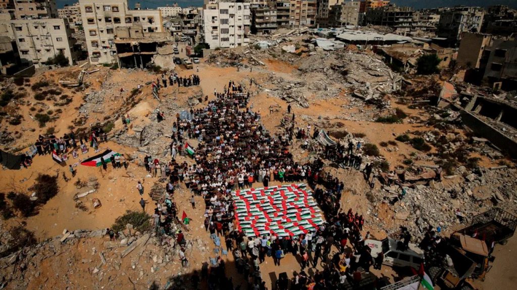Familiares se reúnen alrededor de los restos cubiertos con banderas de palestinos muertos en ataques israelíes.