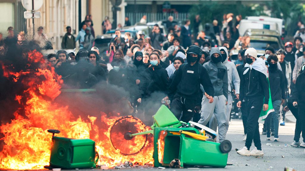 Estudiantes participan en una protesta entre humo y contenedores incendiados en París.