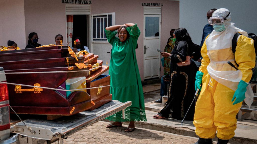 Mujer afectada por la pérdida de un ser querido junto a un féretro durante un funeral en la República Democrática del Congo.