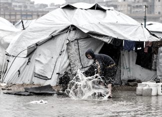 Gaza, un techo de lona frente a la tormenta Niño palestino sacando agua de una tienda inundada en Gaza ante la crisis de refugio.