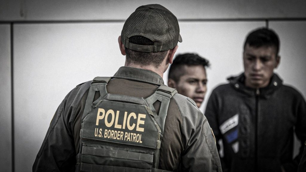 Agente de la Patrulla Fronteriza de Estados Unidos junto a inmigrantes durante un procedimiento migratorio.