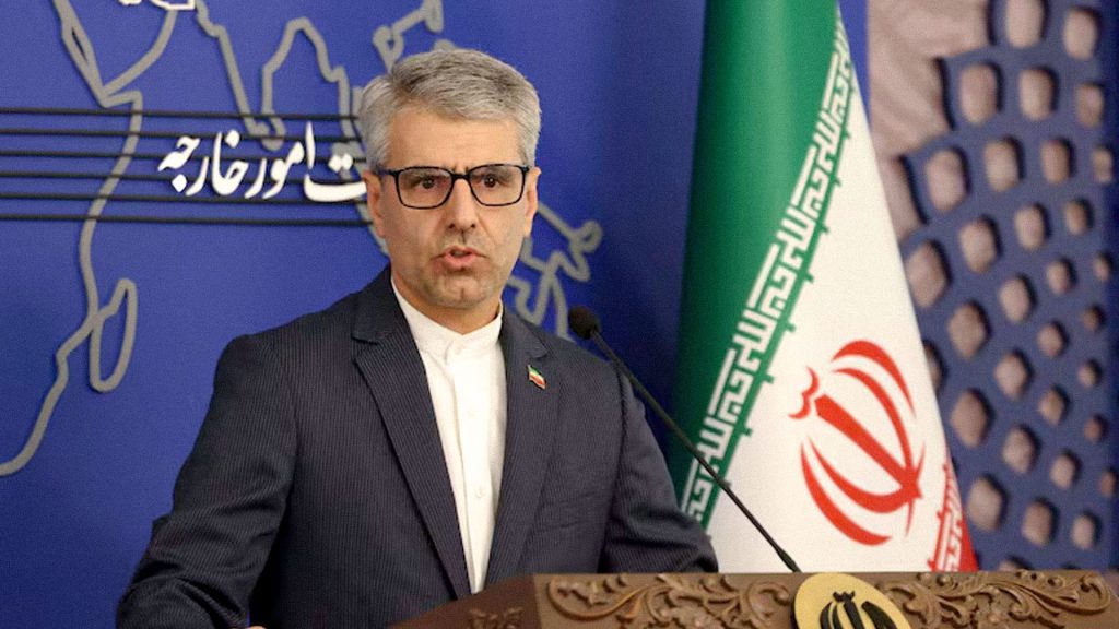 Esmail Baghaei, portavoz de Exteriores de Irán, durante una comparecencia junto a la bandera iraní.