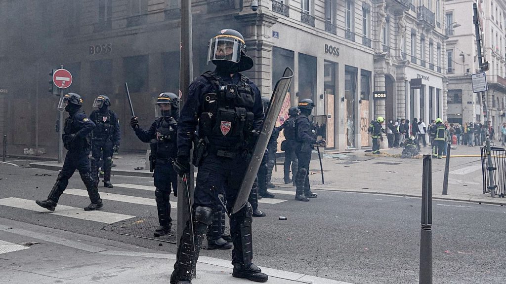 Policías antidisturbios franceses equipados con escudos durante un operativo de seguridad en una calle.