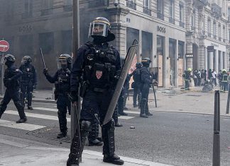 Francia despliega 70.000 policías ante protestas contra Macron Policías antidisturbios franceses equipados con escudos durante un operativo de seguridad en una calle.