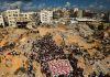 Palestina: Condenamos la continua campaña genocida librada por Israel Palestinos participan en un funeral entre edificios destruidos en Gaza.