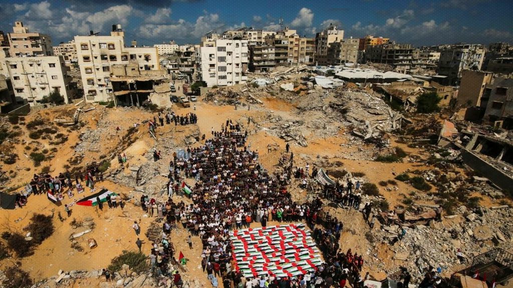 Palestinos participan en un funeral entre edificios destruidos en Gaza.