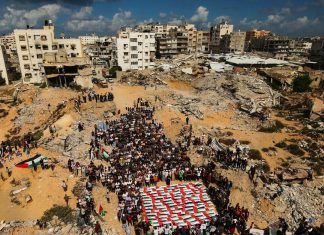 Palestina: Condenamos la continua campaña genocida librada por Israel Palestinos participan en un funeral entre edificios destruidos en Gaza.