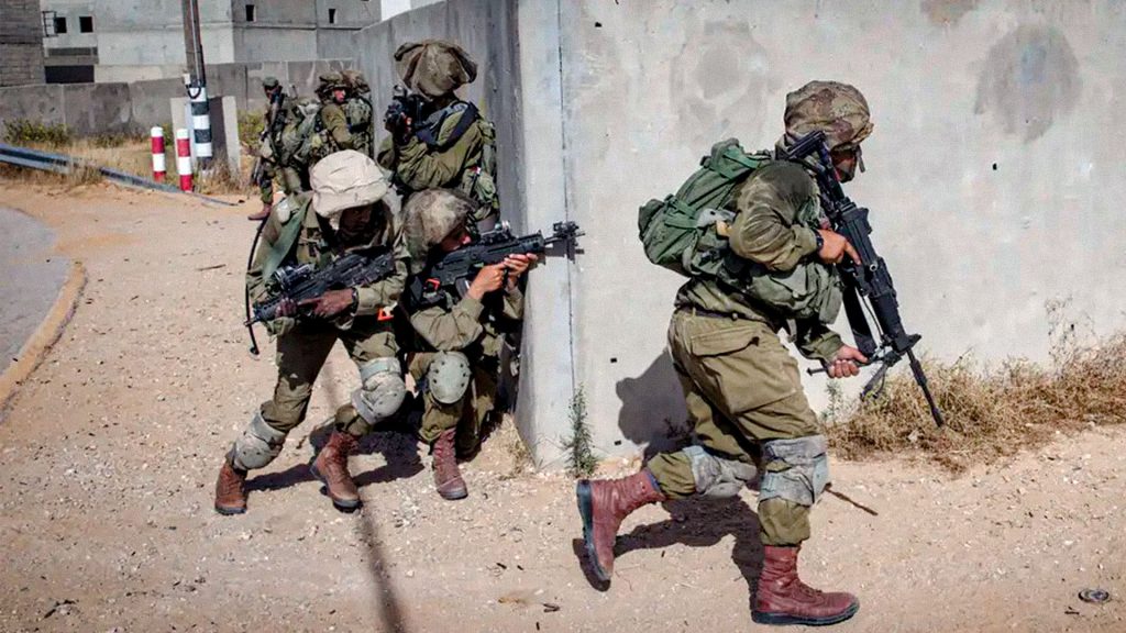 Soldados israelíes armados avanzan junto a un muro durante operaciones militares en Jan Yunis, Gaza.