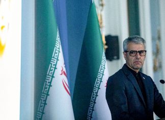 Irán denuncia que Occidente encubre la guerra de agresión de EEUU e Israel Portavoz de Exteriores de Irán, Esmaeil Baqaei, durante una conferencia de prensa junto a la bandera iraní.
