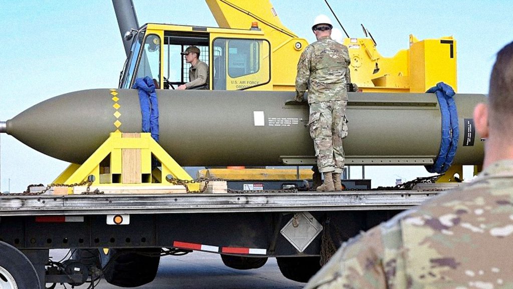 Bomba antibúnker estadounidense GBU-57 MOP de gran tamaño transportada por personal militar en una base aérea.