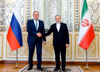 Irán exige un golfo sin tropas extranjeras Representantes diplomáticos de Irán y Rusia estrechan sus manos frente a las banderas de ambos países.