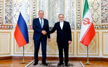 Irán exige un golfo sin tropas extranjeras Representantes diplomáticos de Irán y Rusia estrechan sus manos frente a las banderas de ambos países.