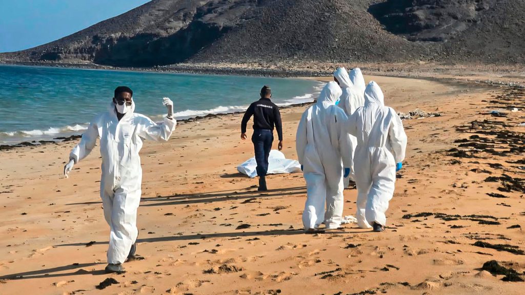 Personal de emergencia con trajes de protección durante labores de recuperación en una playa de Yibuti.