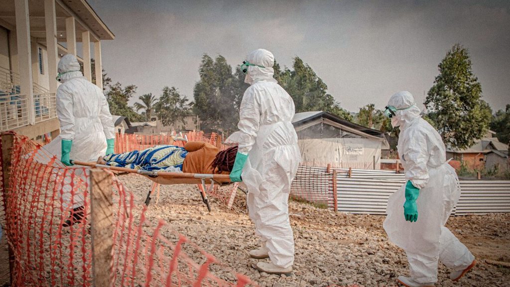 Personal sanitario con trajes de protección traslada a una persona durante una emergencia epidemiológica.