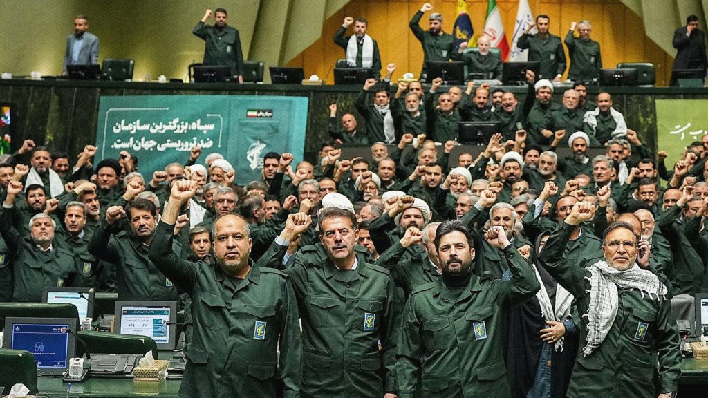 Parlamentarios iraníes con uniformes militares respaldan a la Guardia Revolucionaria durante una sesión parlamentaria en Teherán.