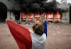 Francia prepara nuevas protestas contra Macron por el costo de vida Manifestante sostiene la bandera de Francia en medio de protestas