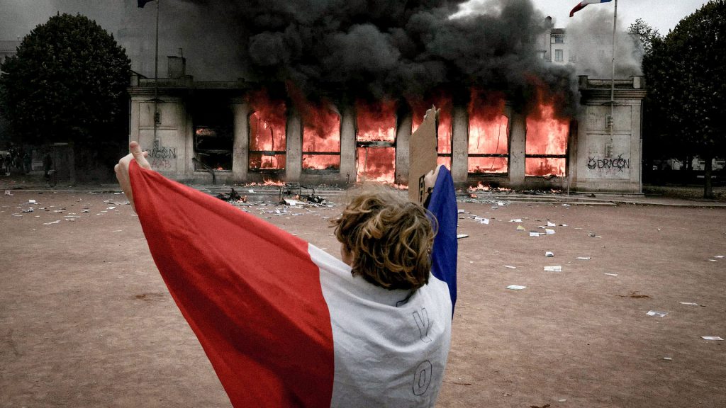 Manifestante sostiene la bandera de Francia en medio de protestas