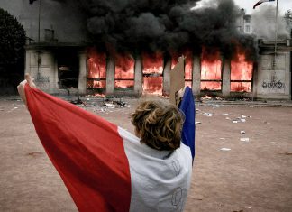 Francia prepara nuevas protestas contra Macron por el costo de vida Manifestante sostiene la bandera de Francia en medio de protestas